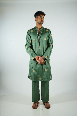Man wearing a green embroidered traditional outfit on a white background