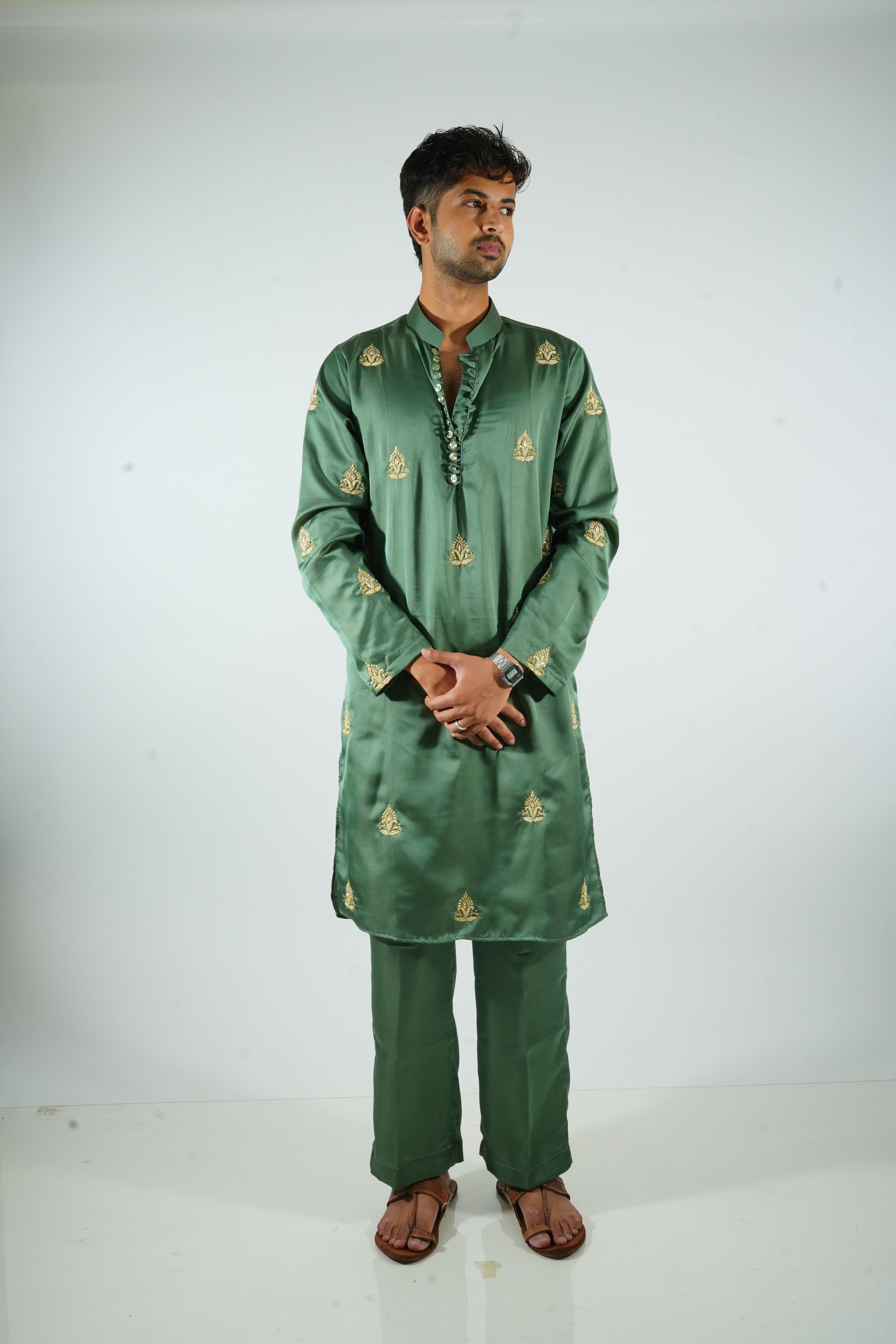 Man wearing a green embroidered traditional outfit on a white background